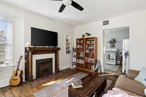 Living room featuring wood finished floors, a fireplace, and a ceiling fan