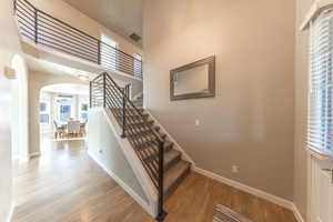 Staircase with arched walkways, a high ceiling, and wood-type floors