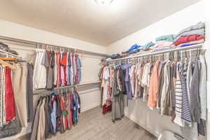 Huge walk-in closet featuring light carpet