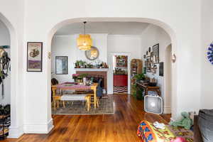 Dining space with crown molding, arched walkways, and wood-type flooring