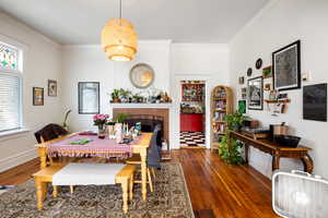 Dining area featuring ornamental molding, a brick fireplace, and dark wood-type flooring