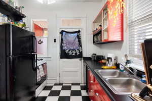 Kitchen featuring open shelves, dark flooring, freestanding refrigerator, dark countertops, and gas range gas stove