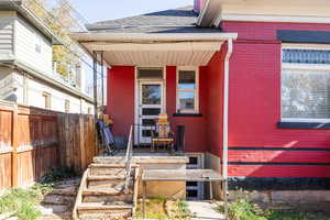 Entrance to property featuring a porch, roof with shingles, and brick siding