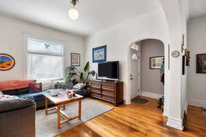 Living area featuring arched walkways and light wood finished floors