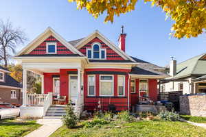 Victorian home with covered porch, a chimney, and a front yard