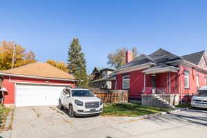 View of side of home featuring a chimney, a garage, an outdoor structure, driveway, and roof with shingles