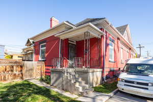 View of front facade with a porch, a chimney, and roof with shingles