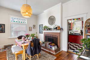 Dining area with a fireplace, crown molding, and dark wood-style flooring