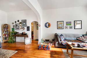 Living area with wood finished floors and arched walkways