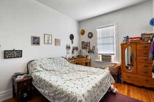 Bedroom with wood finished floors and cooling unit