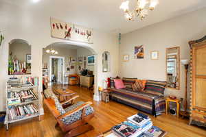 Living room featuring a chandelier, wood-type flooring, and arched walkways