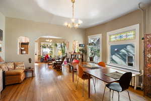 Dining space featuring arched walkways, a chandelier, and hardwood / wood-style floors