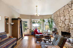 Living room with plenty of natural light, wood-type flooring, a fireplace, and a chandelier