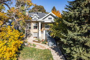 View of front of home with stairs, a front yard, and view of wooded area