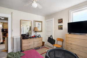 Carpeted bedroom featuring radiator heating unit and ceiling fan