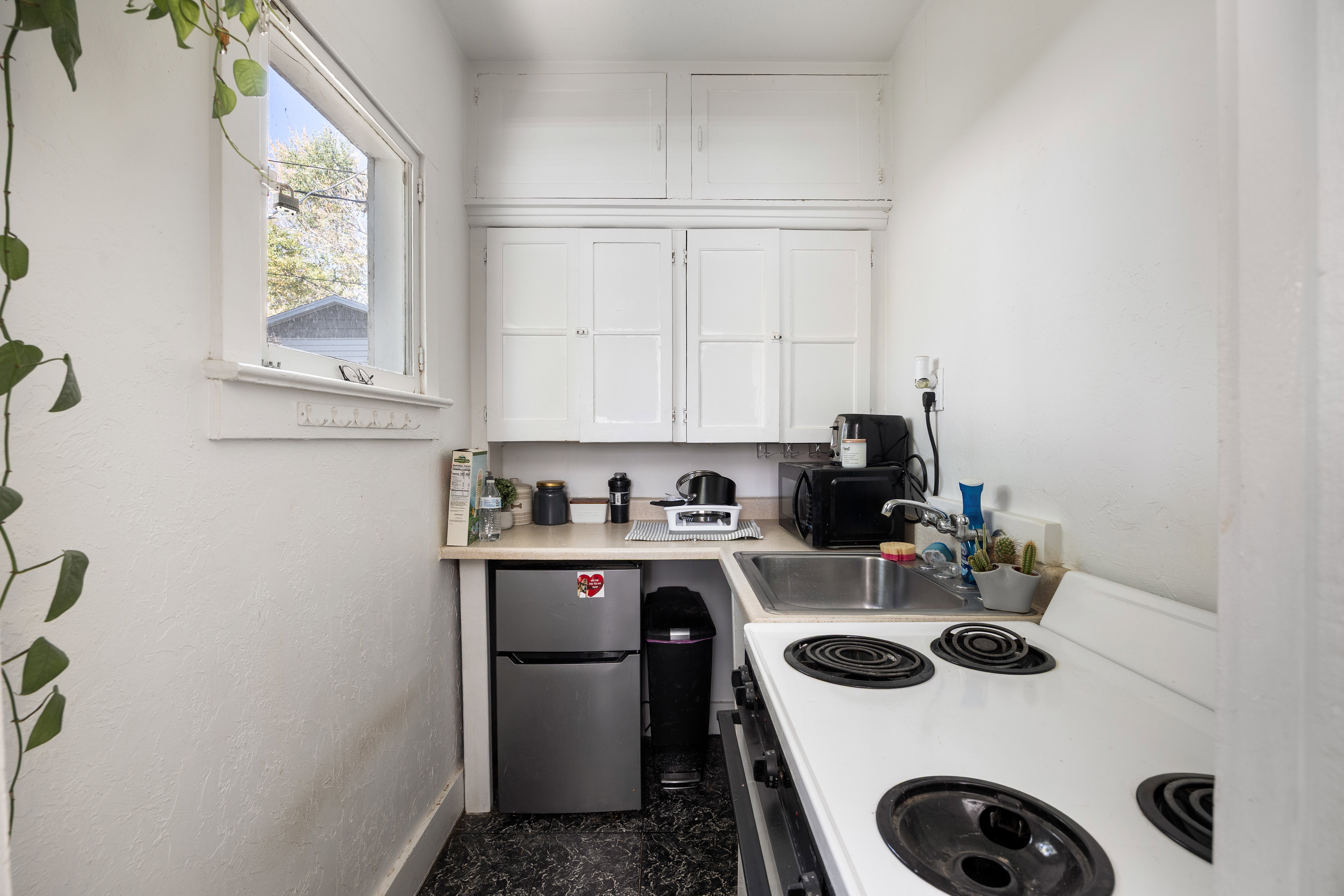 Kitchen featuring white range with electric stovetop, white cabinets, light countertops, freestanding refrigerator, and black microwave