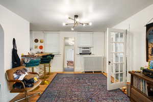 Kitchen with wood finished floors, radiator, a chandelier, a kitchen breakfast bar, and cooling unit