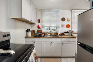 Kitchen featuring appliances with stainless steel finishes, white cabinets, and butcher block countertops