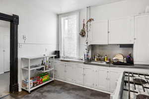 Kitchen featuring stainless steel counters, white cabinetry, white appliances, and backsplash