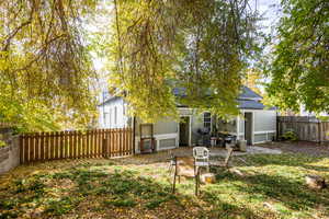 Back of house with a shingled roof, a fenced backyard, and a patio