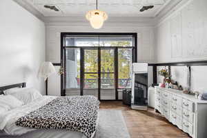 Bedroom with an ornate ceiling, wood finished floors, and crown molding