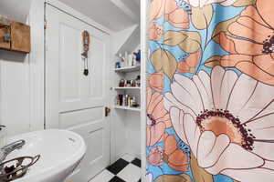 Bathroom with a shower with shower curtain and tile patterned floors