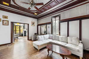 Living room with ceiling fan, wood finished floors, and ornamental molding