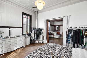 Bedroom featuring an ornate ceiling, dark wood-style floors, and ornamental molding