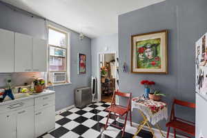 Kitchen with light floors, white cabinetry, light countertops, and freestanding refrigerator
