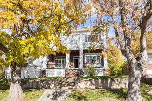 Traditional home with brick siding, a porch, a fenced front yard, and stairway