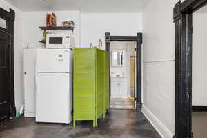 Kitchen featuring white appliances and concrete floors