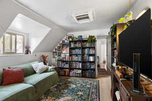 Sitting room with cooling unit, light wood-style flooring, and lofted ceiling