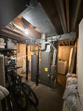 Unfinished below grade area featuring heating unit, washer / dryer, and water heater