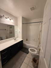 Full bathroom with light tile patterned floors, vanity, and shower / bath combo