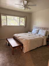 Carpeted bedroom featuring ceiling fan and a textured ceiling