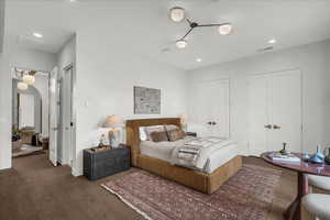 Bedroom featuring arched walkways, multiple closets, dark wood-style flooring, and recessed lighting