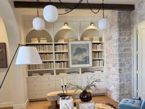 Living area featuring beamed ceiling, built in shelves, and wood finished floors