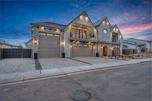 View of front of home with a balcony, stone siding, decorative driveway, and an attached garage