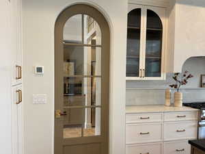 Detailed view of dark wood-style floors, two tone cabinets, high end stainless steel range, dark stone countertops, and recessed lighting