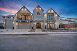 View of front of property with stone siding, a balcony, french doors, and decorative driveway