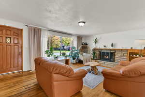 Living room with a textured ceiling, a fireplace, and light wood-style floors