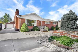 Ranch-style house with a chimney, brick siding, a garage, and an outdoor structure