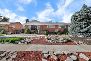 View of front of house featuring brick siding and a chimney
