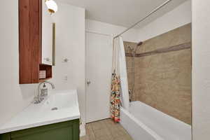 Bathroom with shower / bathtub combination with curtain, light tile patterned flooring, vanity, and a textured ceiling