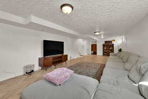 Living room featuring a textured ceiling and stairway