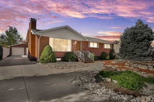 Ranch-style home with an outdoor structure, a garage, a chimney, and brick siding