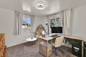 Office area featuring dark colored carpet and baseboards
