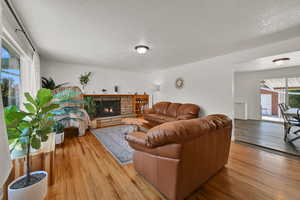 Living area with a textured ceiling, light wood-type flooring, and a fireplace