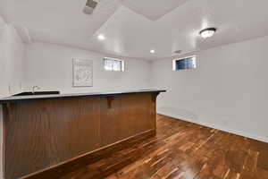 Indoor bar with a textured ceiling, dark wood-type flooring, plenty of natural light, and recessed lighting