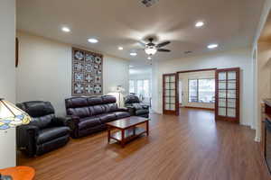 Living area featuring recessed lighting, commercial grade LVP light wood finished floors, ceiling fan, and french doors.